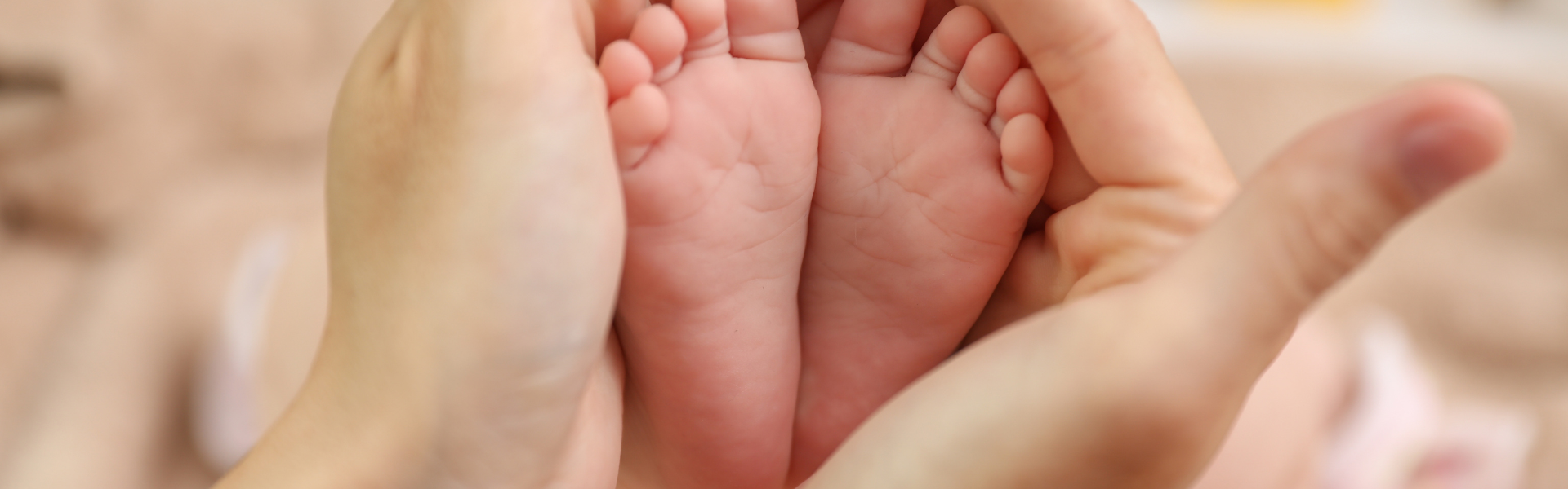 Piedini di neonato tra le mani di un genitore, simbolo dell’indennità di maternità e del congedo per la nascita di un figlio